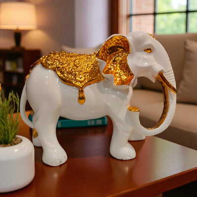 Decorative white elephant figurine with gold accents on a table in a living room setting.