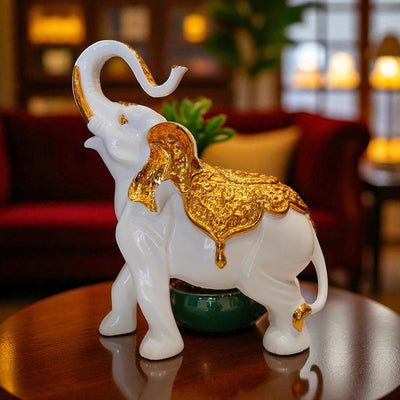 Decorative white elephant figurine with gold accents on a reflective surface.