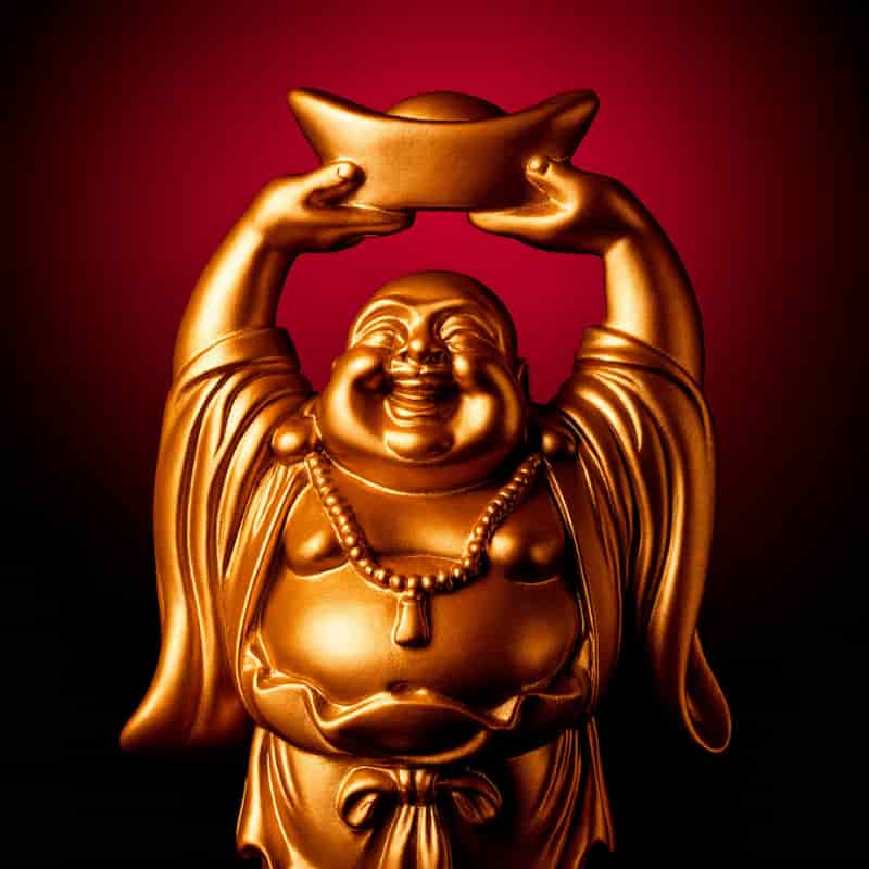 Golden Laughing Buddha idol holding an ingot above his head, symbolizing prosperity and happiness, perfect for home decor and gifting by Motumal Giftwala.