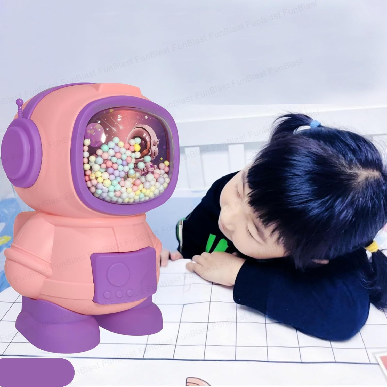 Child interacting with a pink and purple robot toy filled with colorful beads on a white surface.