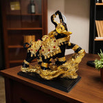 Decorative statue of a bull with gold and black finish on a wooden surface.