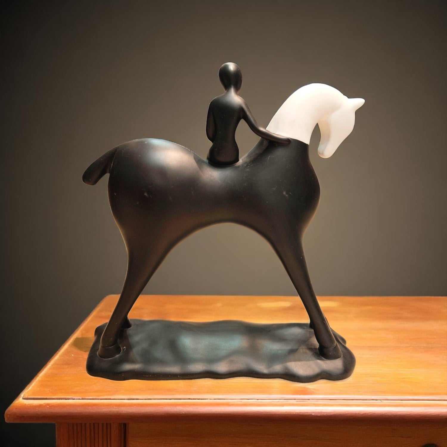 Artistic black horse statue with rider – back view