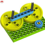 Toy construction set with gears on a green baseplate, featuring a brand logo in the corner.