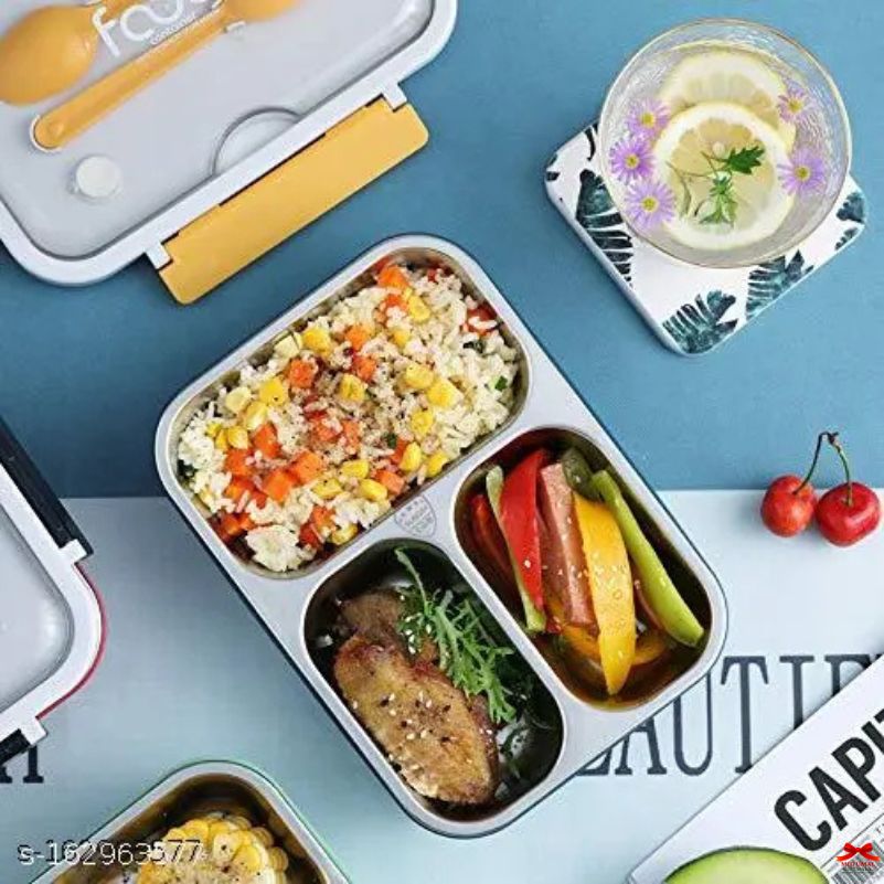 Meal prep container with compartments of food, a glass of lemonade, and cherries on a blue surface.