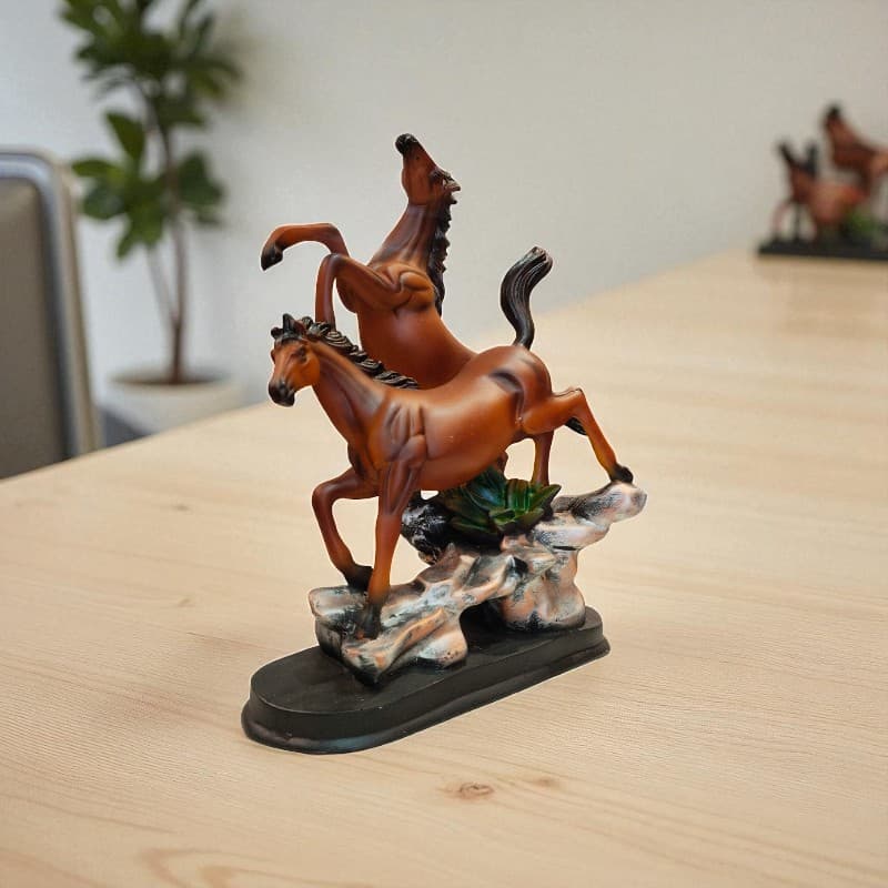 Statue of two horses rearing on a wooden surface with a blurred background