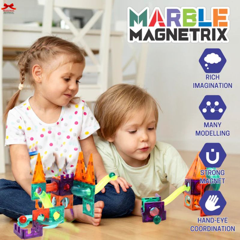 Two children playing with colorful marble magnetrix toys on a wooden floor.