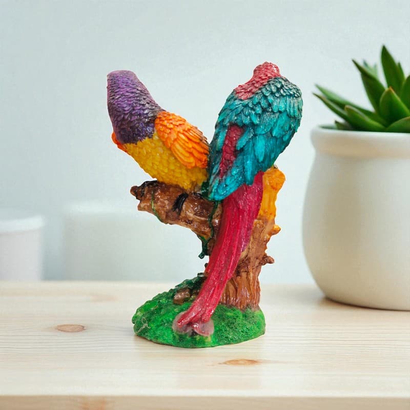 Colorful parrot figurine on a branch with a plant in the background