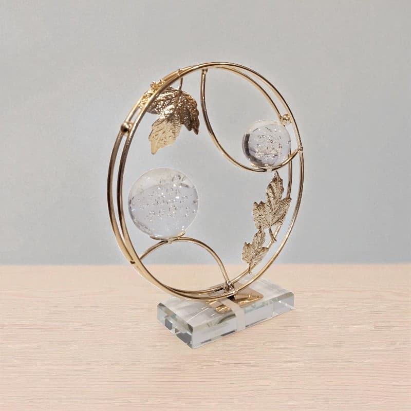 Decorative object with gold circular frame and crystal balls on a beige surface