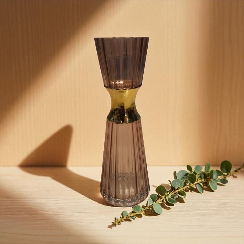 Smoky glass vase on a wooden surface with a branch of eucalyptus leaves.
