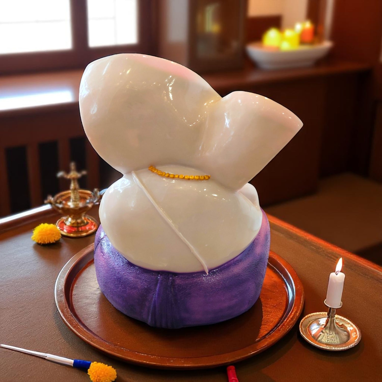 Back view of Ganesha idol in purple dhoti seated on round tray