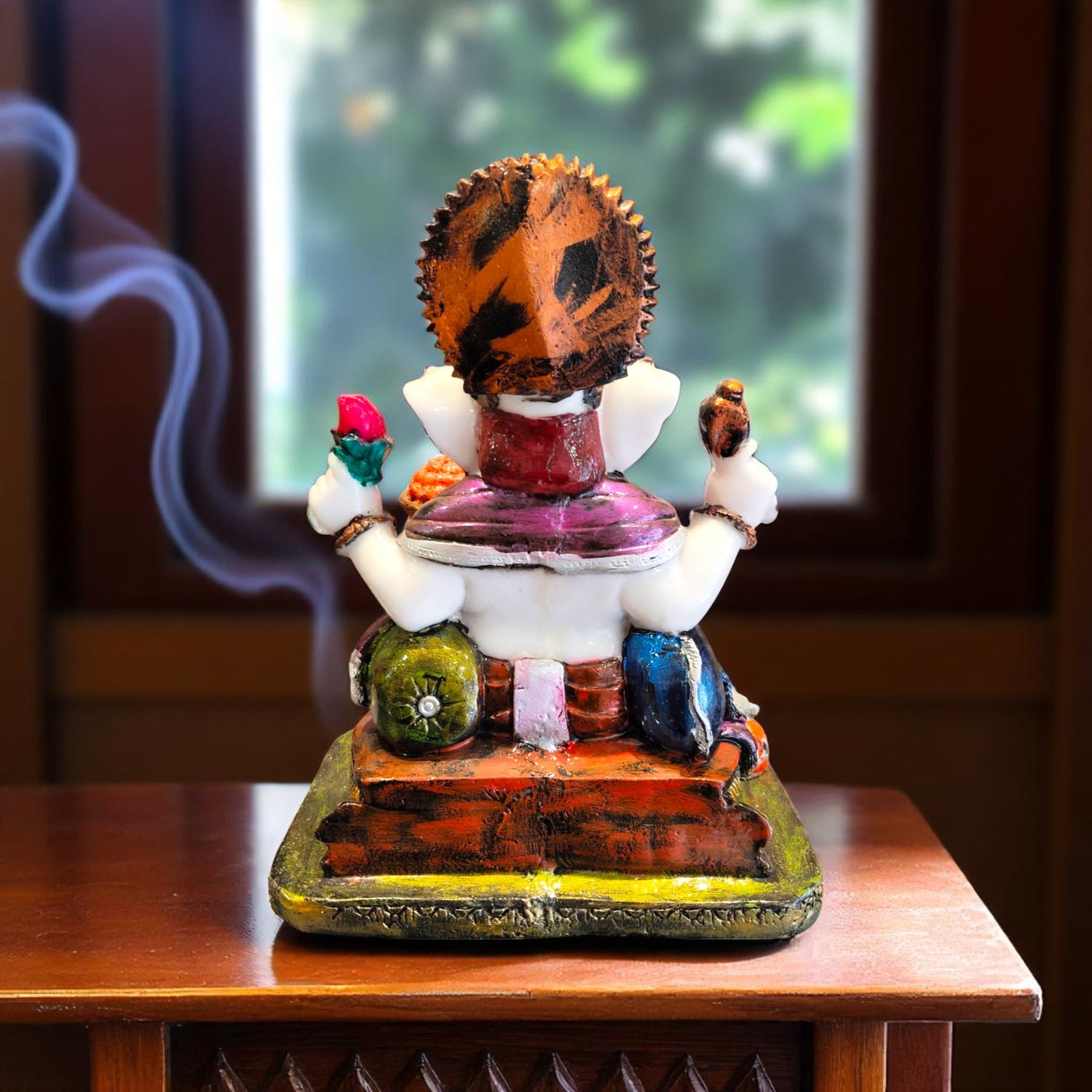 Back view of traditional Ganesha idol with orange crown and multicolor base