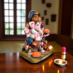 Side angle of Ganesha holding modak and lotus, seated on decorated base