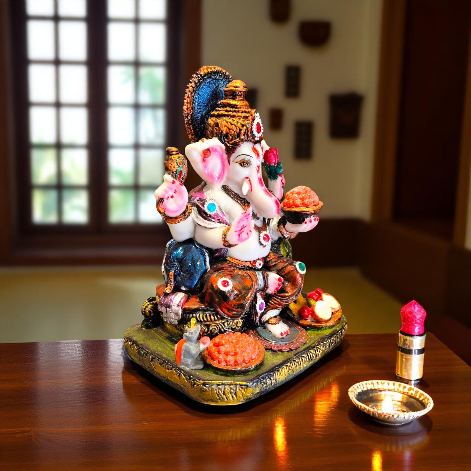 Side angle of Ganesha holding modak and lotus, seated on decorated base