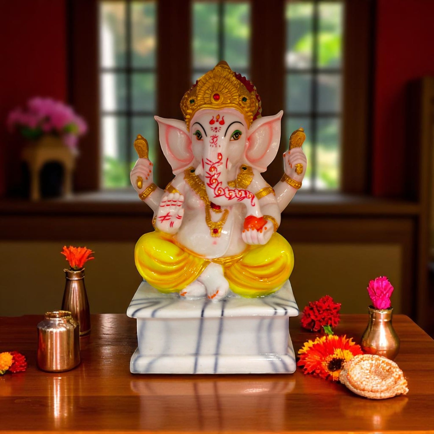 Front view of white ganesha idol seated on marble base with diya