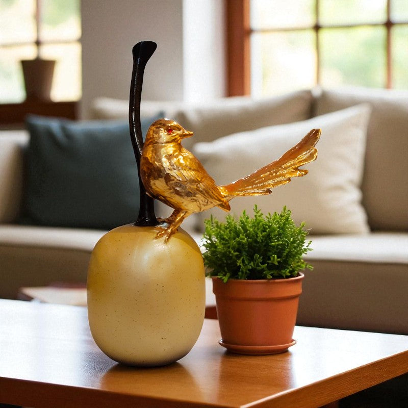 Decorative bird sculpture on a spherical base with a potted plant on a table in a living room.