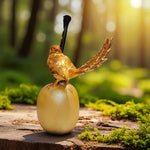 Gold bird figurine on a wooden log with a blurred forest background