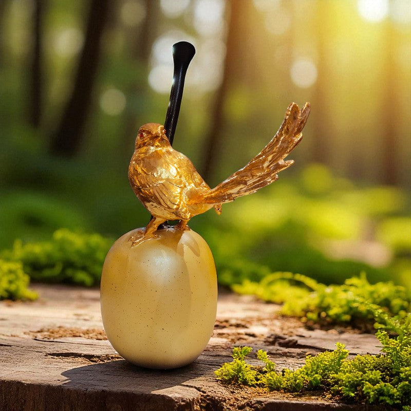 Gold bird figurine on a wooden log with a blurred forest background