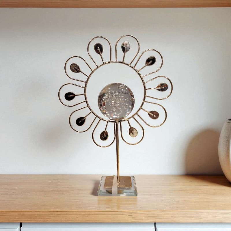 Decorative metal sculpture on a wooden surface with a plain background