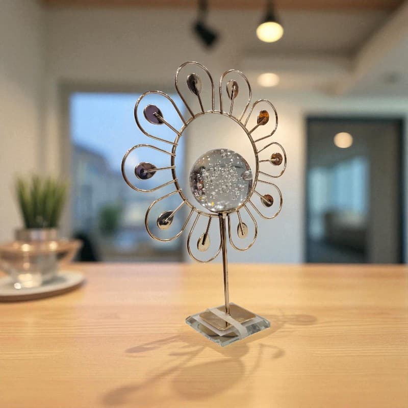 Decorative metal and glass object on a wooden surface with a blurred indoor background