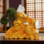 Gold and white statue of a seated figure on coins with a blurred indoor background