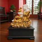 Gold and white statue on a black base in a room with red walls and wooden floor.