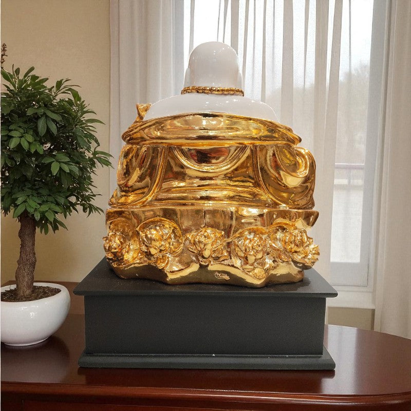 Decorative golden object on a black base with a plant in the background