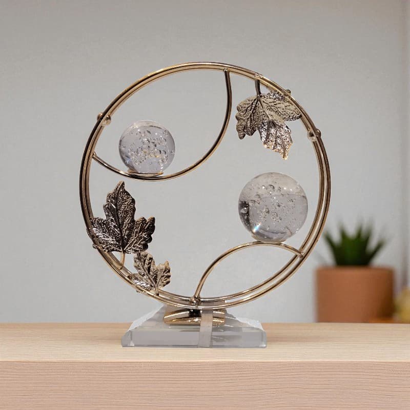 Decorative piece with gold circular frame, silver leaves, and crystal balls on a wooden surface.