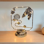 Decorative lamp with feathers and lights on a wooden surface