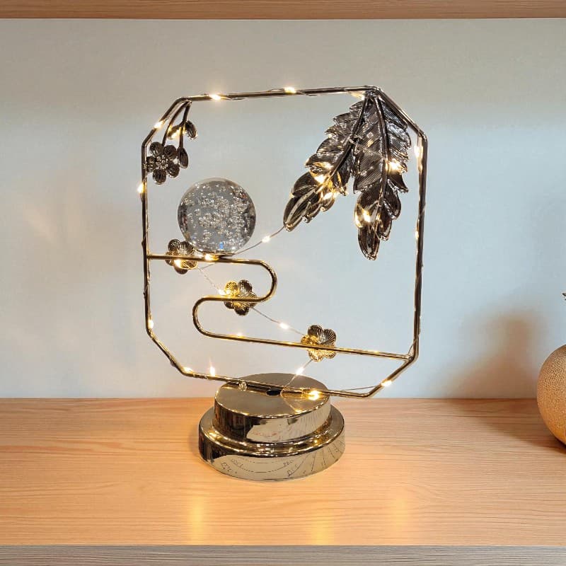 Decorative lamp with feathers and lights on a wooden surface