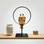 Decorative sculpture of two figures embraced by a circular frame on a wooden surface with a plain background