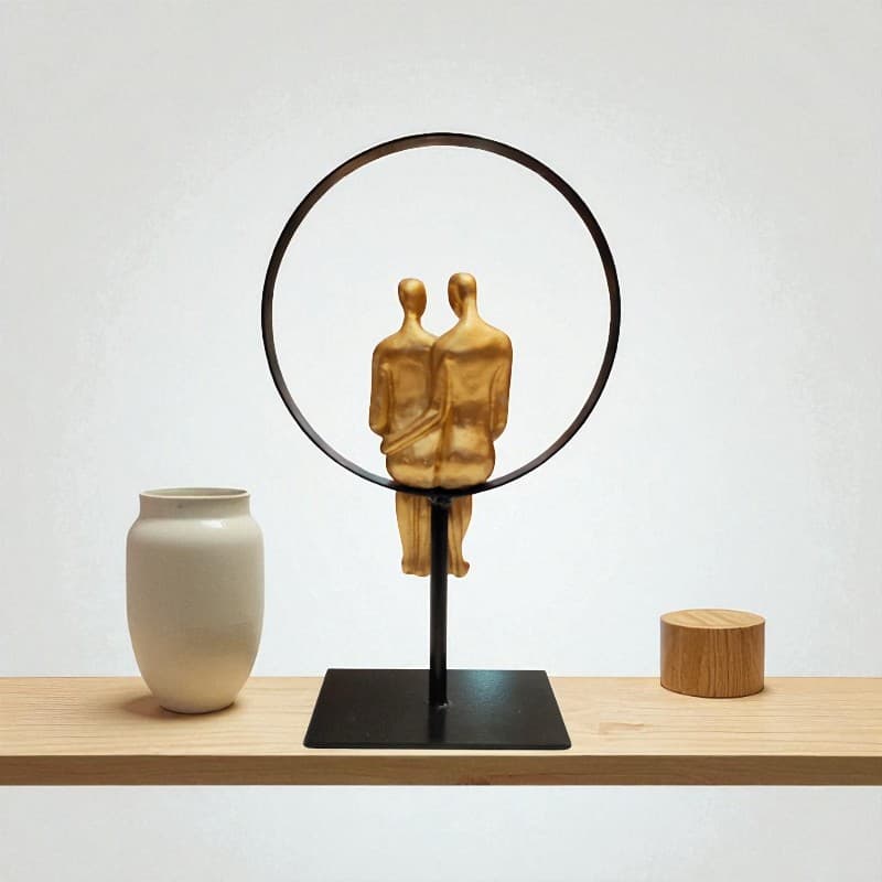 Decorative sculpture of two figures embraced by a circular frame on a wooden surface with a plain background