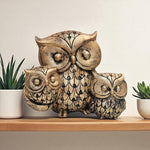 Decorative owl sculpture on a shelf with plants in the background