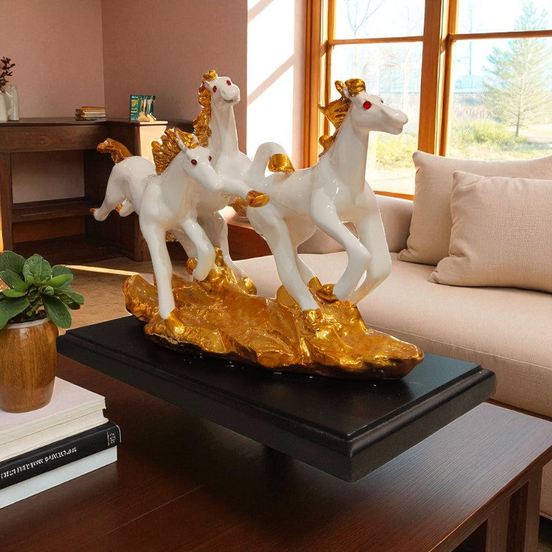 Decorative sculpture of three white horses with gold accents on a black base in a living room.