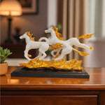 Decorative sculpture of three white horses with gold manes on a black base, placed on a wooden surface.