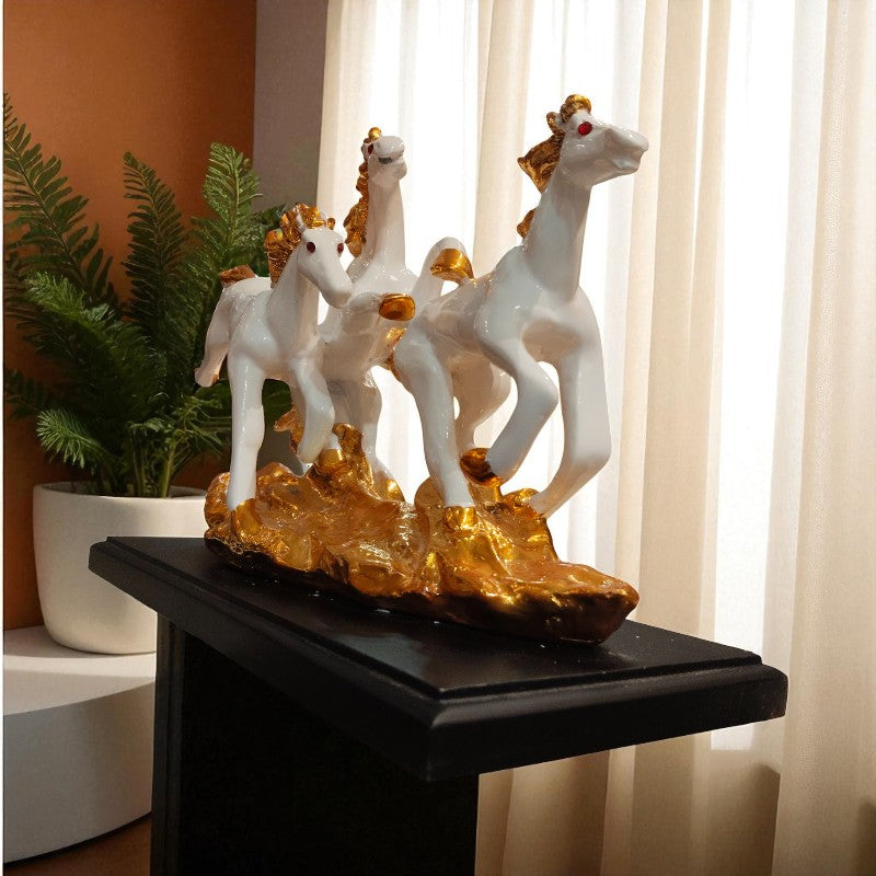 Decorative sculpture of three horses on a pedestal with a plant and curtain in the background