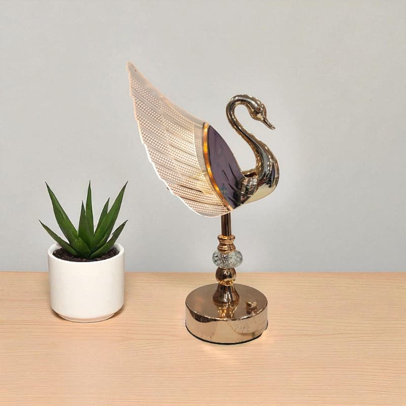 Decorative swan lamp on a wooden surface with a plant in the background