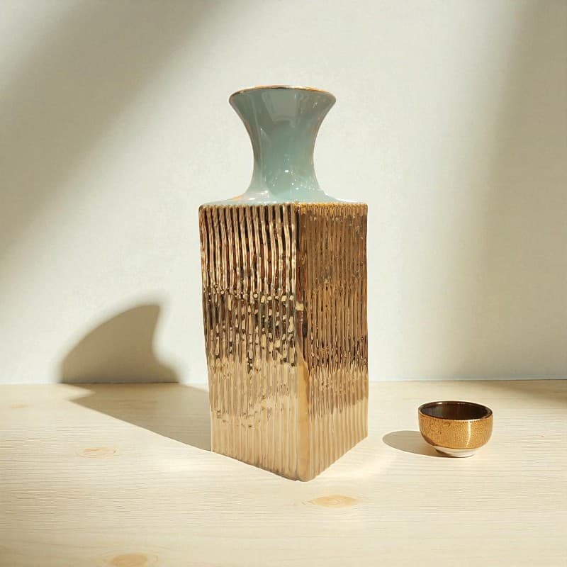 Ceramic vase on a wooden block with a small bowl on a neutral background
