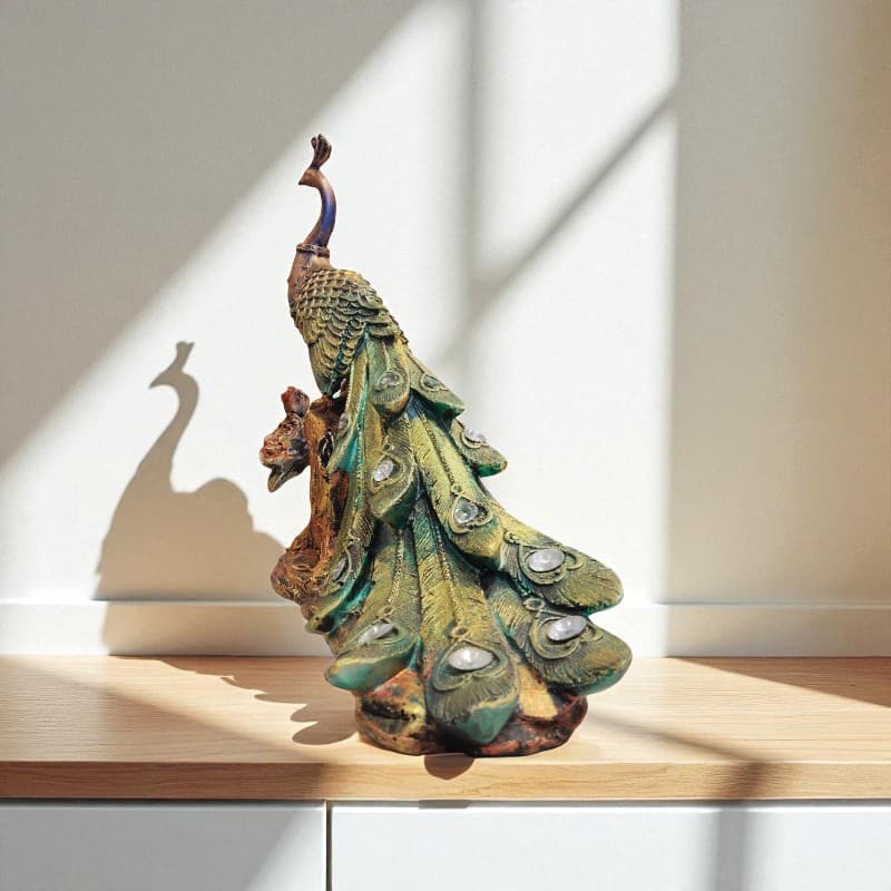 Decorative peacock statue on a wooden surface with a neutral background