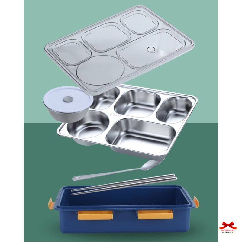 Stainless steel compartment tray with lid, blue plastic container, and metal utensils on a green background.