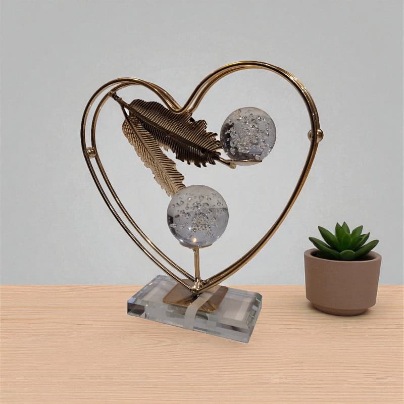 Decorative heart-shaped sculpture with glass spheres on a wooden surface