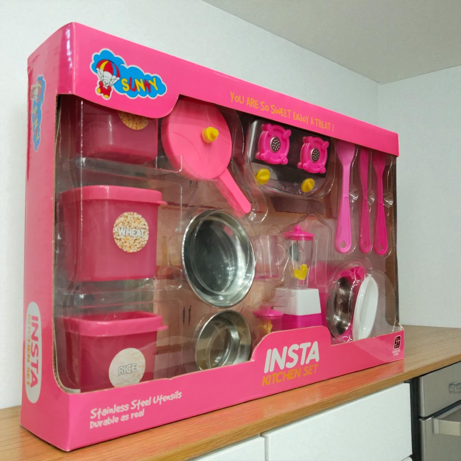Side angled view of Insta Kitchen Set box with stainless steel utensils and pink blender