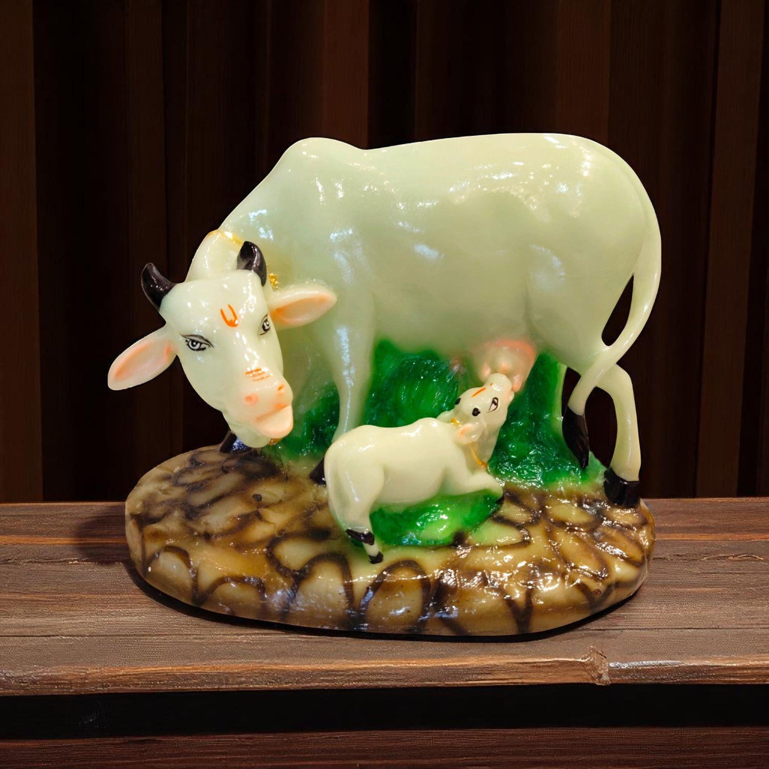 Front view of cow and calf resin idol on green base