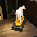 Rear angle of golden cow and calf statue on black base