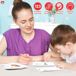 Woman and child engaged in educational activity with worksheets and markers, against a light blue wall with educational icons.