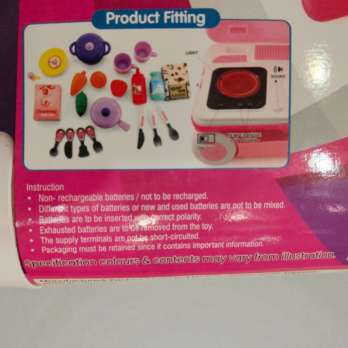 Close-up of included toy kitchen accessories like pans, cups, utensils, and pretend food items.