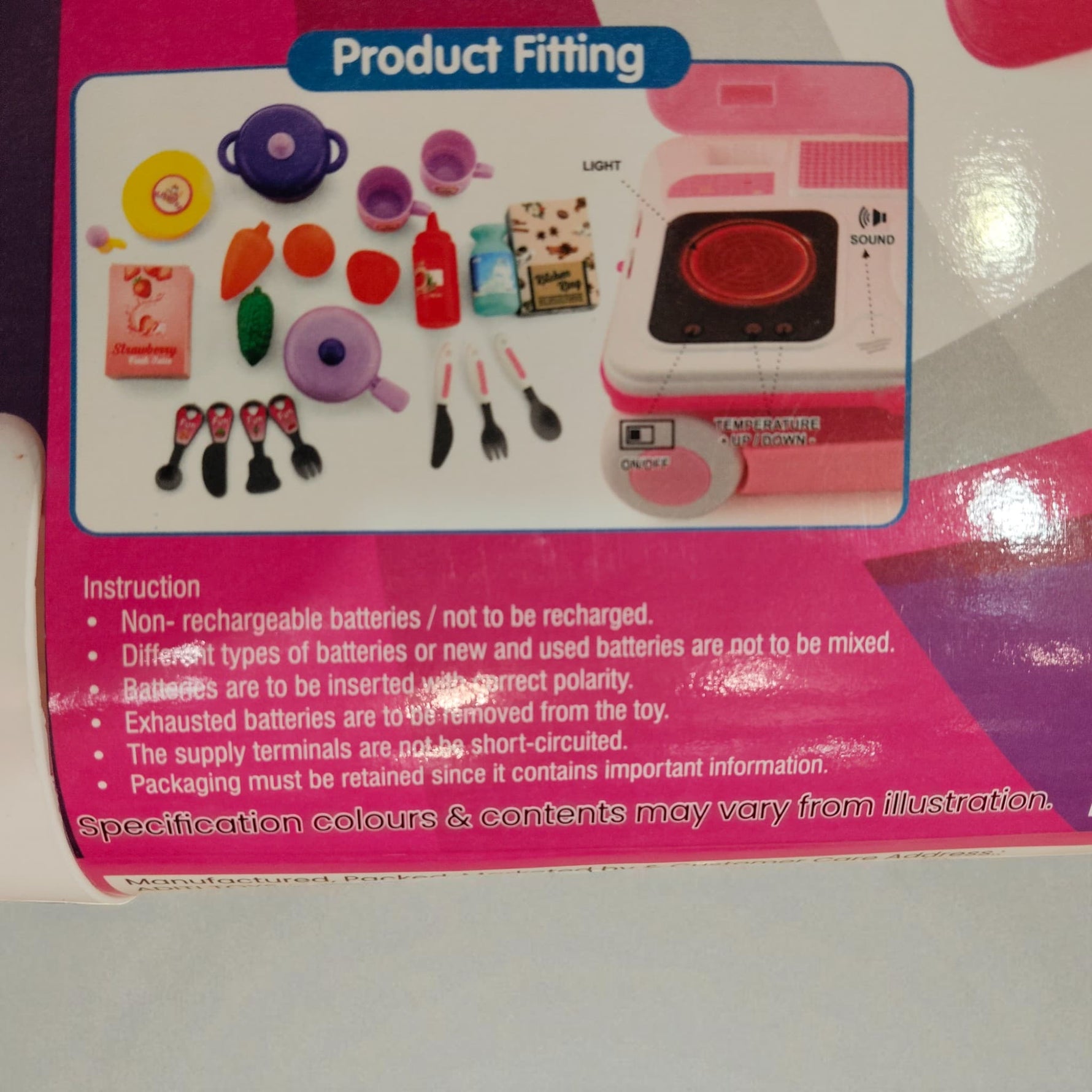 Close-up of included toy kitchen accessories like pans, cups, utensils, and pretend food items.