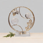Decorative piece with gold leaf design and crystal balls on a light gray background