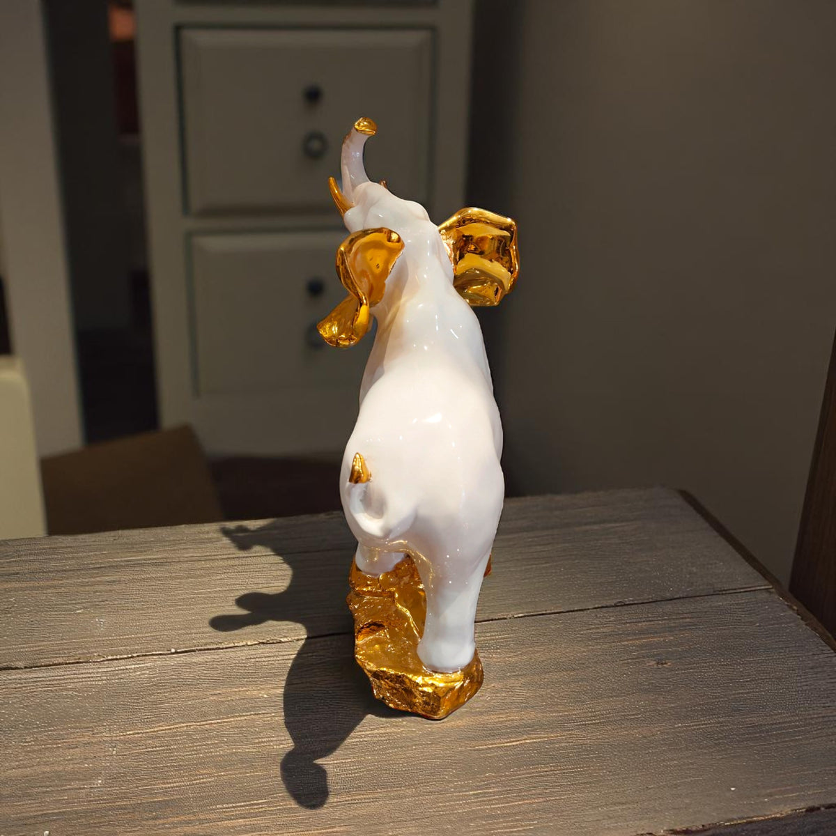 Rear view of white elephant showpiece with golden details on ears and feet