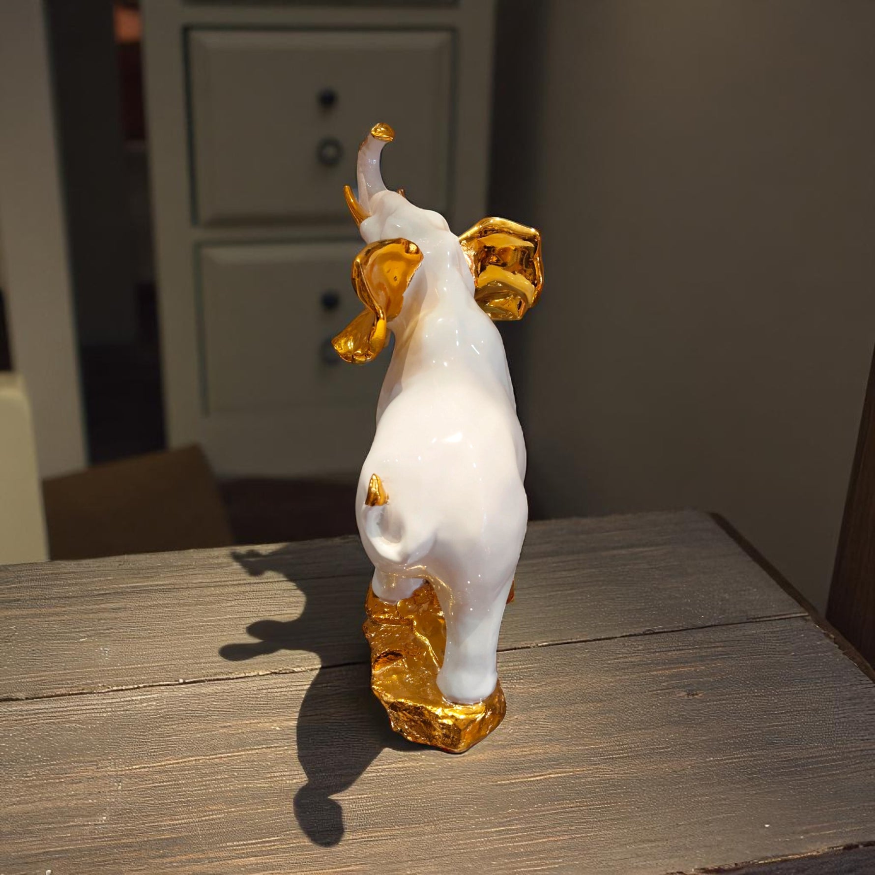 Rear view of white elephant showpiece with golden details on ears and feet
