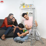 Family of four playing with a model Eiffel Tower in a living room.